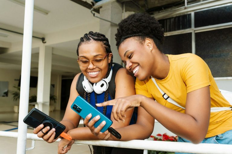 Two smiling women looking at a smartphone together